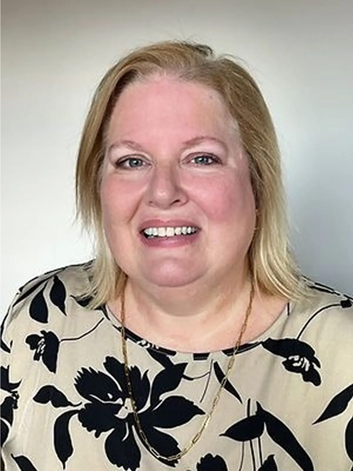Smiling person in floral print blouse.