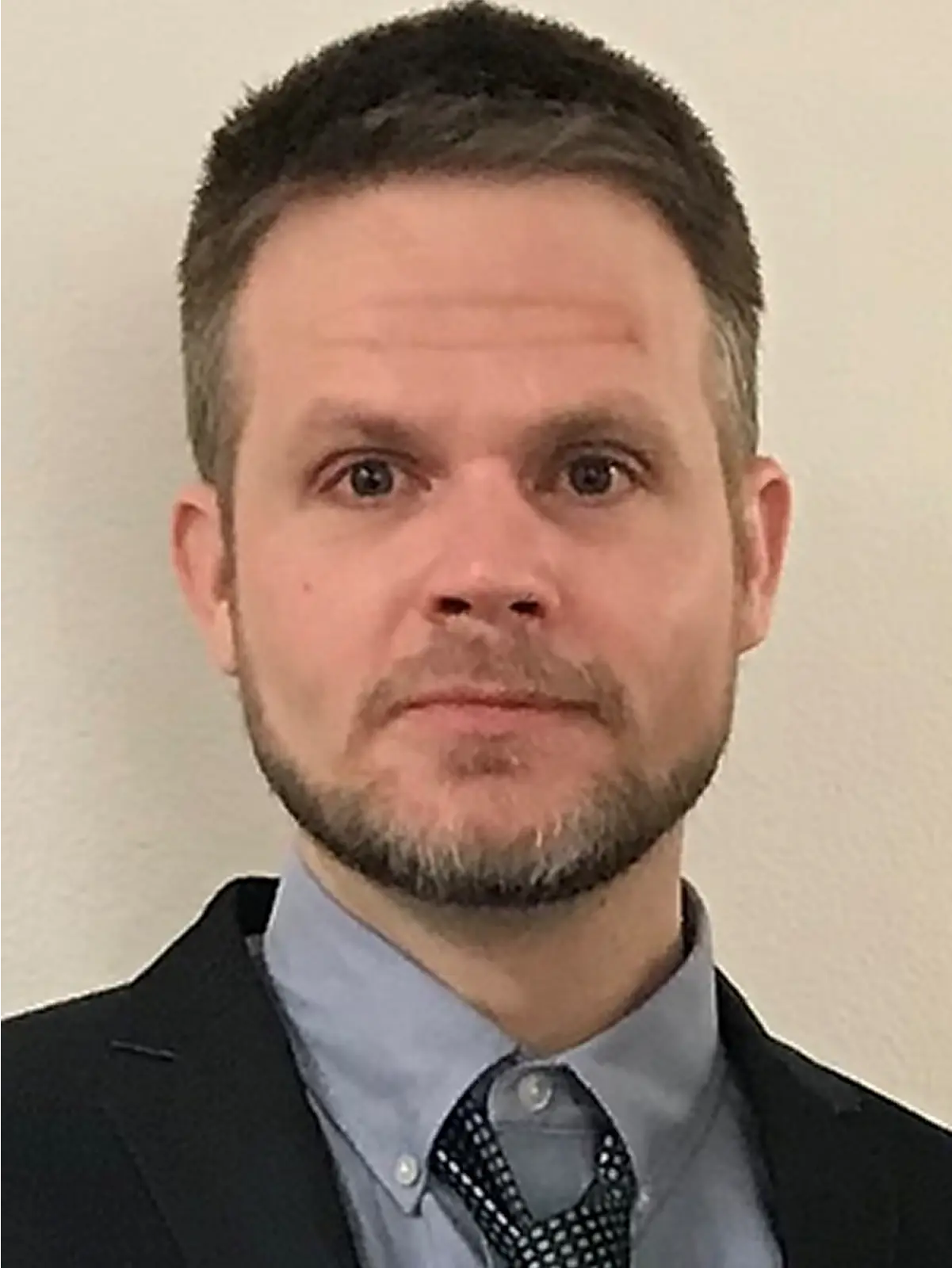 Man in suit with short hair and beard.