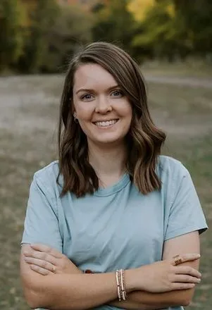 Smiling woman outdoors in a blue shirt.